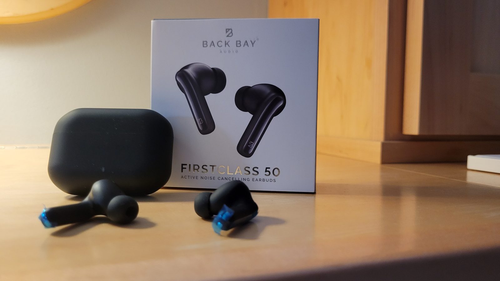 Back Bay Audio FirstClass 50 wireless earbuds and charging case on a table